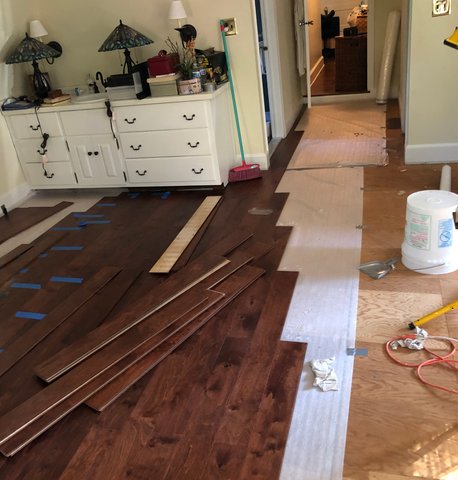 Hardwood flooring installation in progress — dark planks being laid