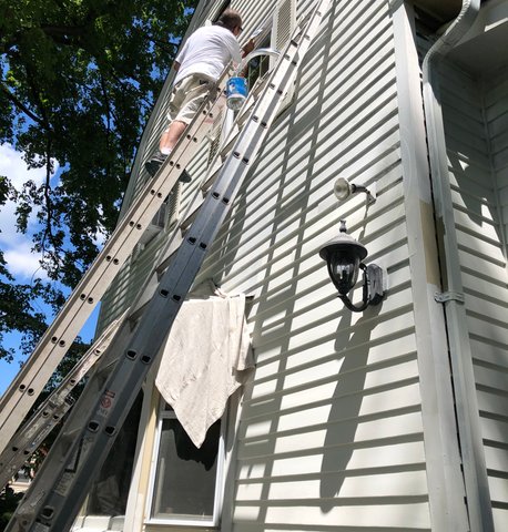 Exterior house painting in progress — crew working on siding